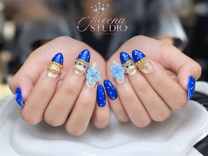 Blue polka dot almond nails with gold bands, crystals and 3D flowers