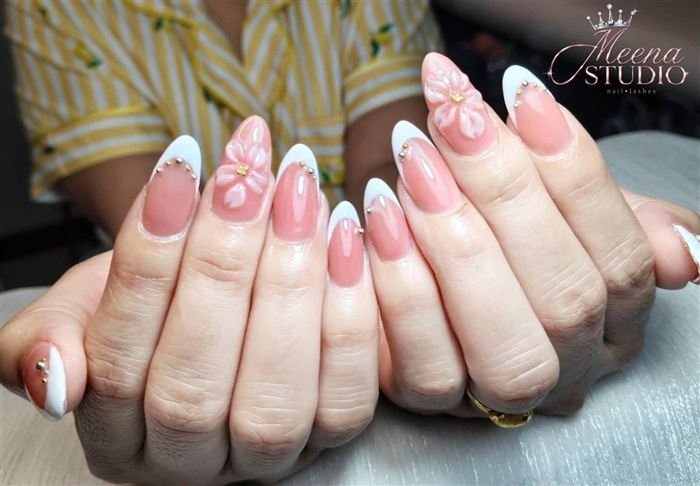 Peach almond nails with white French tips, gold beads and a 3D flower